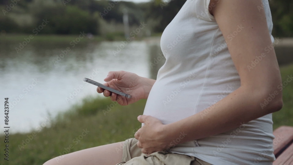 Pregnant woman using mobile phone in park Pregnant woman using mobile phone in park