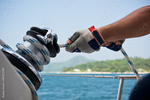 Winch and sailors hands on a sailboat