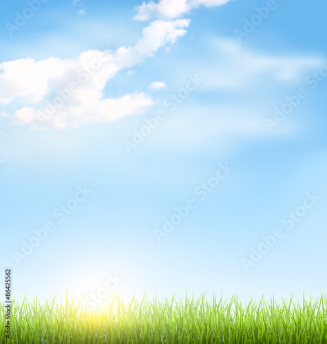 Green grass lawn with clouds and sun on blue sky