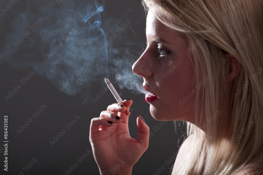 Obraz premium Frau mit Zigarette raucht im Schatten Nahaufnahme