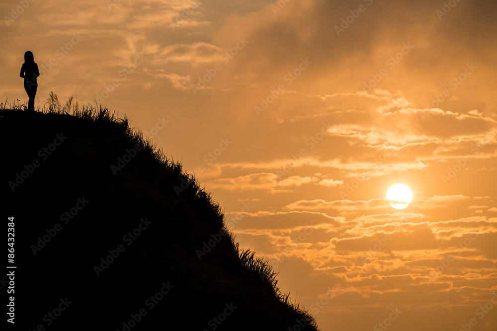 Women standing on the top of mountain with beautiful sunrise. In Phu Chi Fah national park of Chiang Rai province of Thailand.