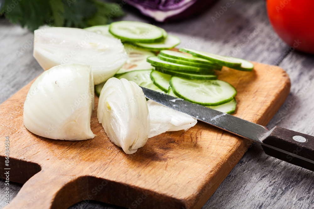 Chopped vegetables: onion and cucumber on cutting board Chopped vegetables: onion and cucumber on cutting board