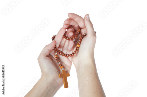 Brown wooden rosary entwined around two female hands during a payer on a white background