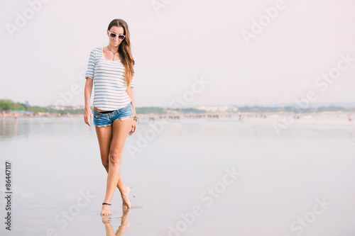 Beautiful happy sexy woman with long legs walking on the beach