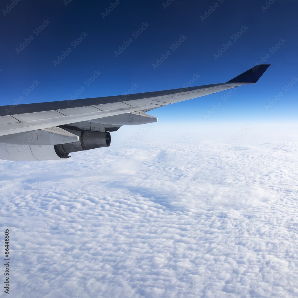 Obraz premium Wing of airplane flying above the clouds in the sky