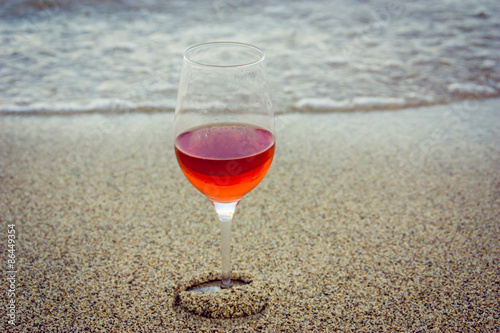 Glass of red wine in the sand