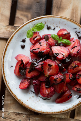 Strawberries with chocolate on a plate, rustic wooden surface