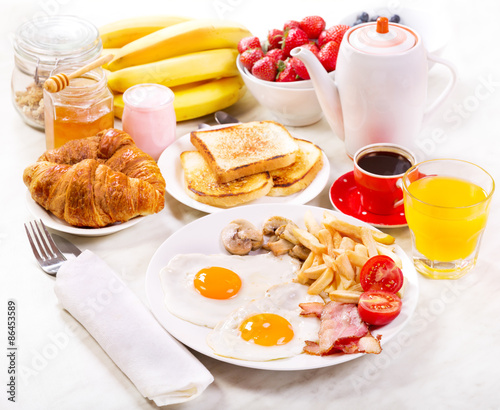 Breakfast  with fried eggs, coffee, orange juice, toasts and fru
