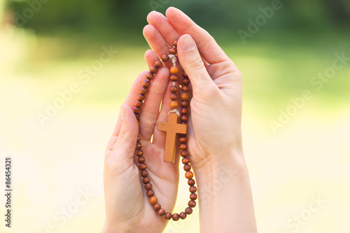 Hand holding wooden rosary beads in close up
