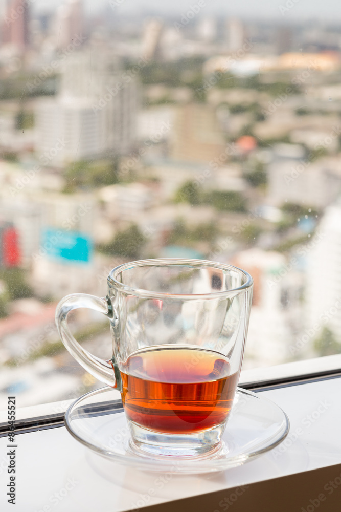 a glass with tea at the window with soft blur city view in background a glass with tea at the window with soft blur city view in background