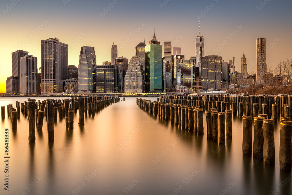 Long exposure of the Lower Manhattan skyline at sunset with an old Brooklyn pier in the foreground