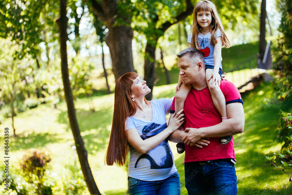 Fototapeta premium A young family, a pregnant mother, father, daughter