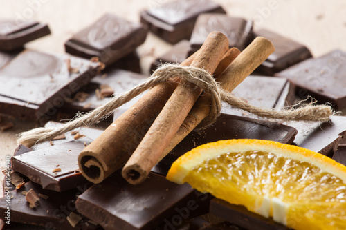 Chocolate with cinnamon sticks and orange slice, selective focus