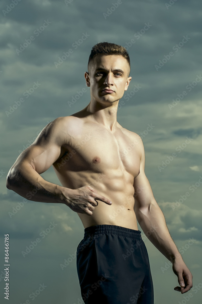 Handsome bodybuilder on blue sky background
