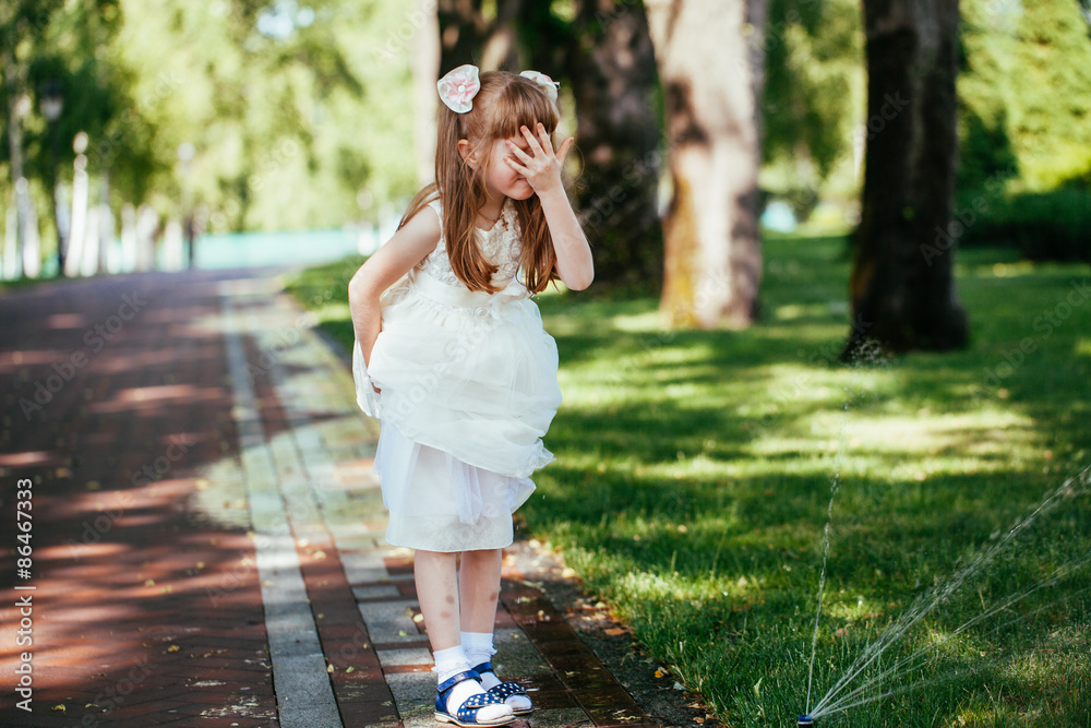 Happy little girl playing with a spray of water in the park Happy little girl playing with a spray of water in the park