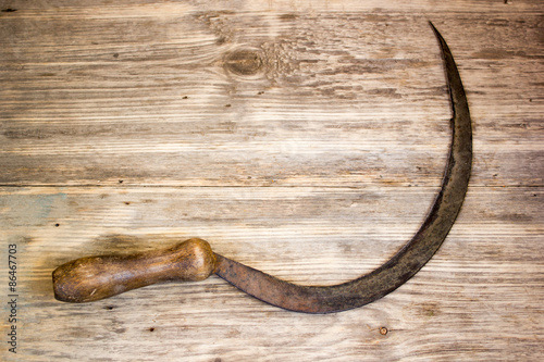 sickle on wooden background photo
