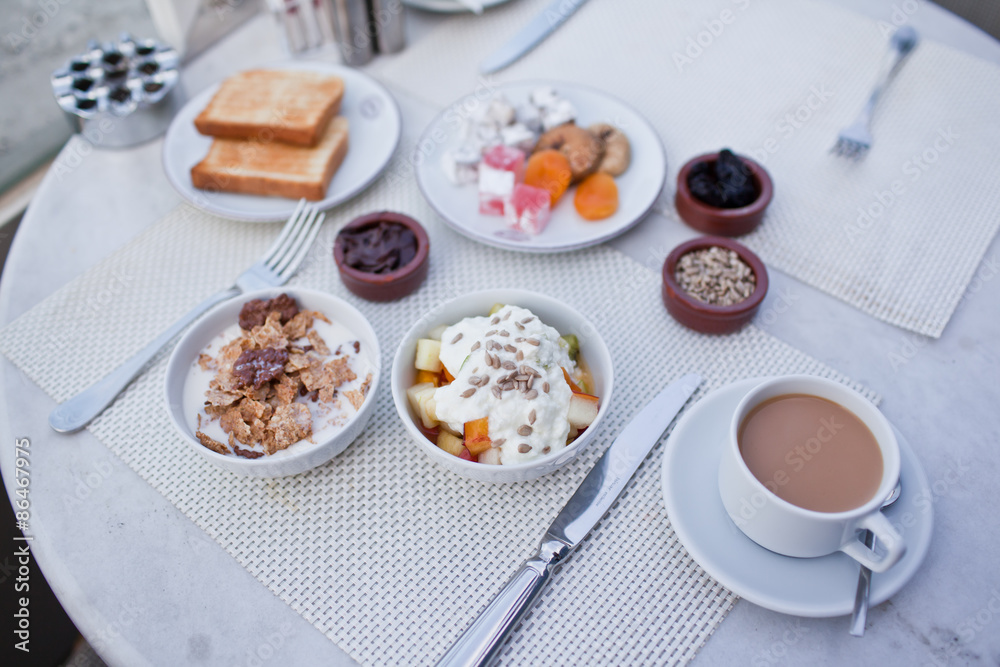 breakfast with cup of black coffee, musli and yoghurt on balcony