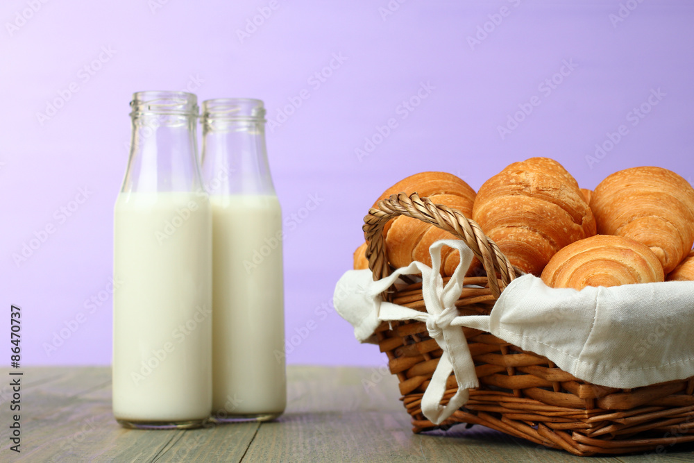 Croissants in a basket and a glass of milk on wooden background Croissants in a basket and a glass of milk on wooden background
