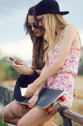 Beautiful young women using mobile phone in the street.