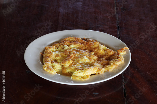 Thai omelet in dish on wooden table