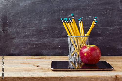 Back to school background with tablet, pencils and apple over chalkboard photo