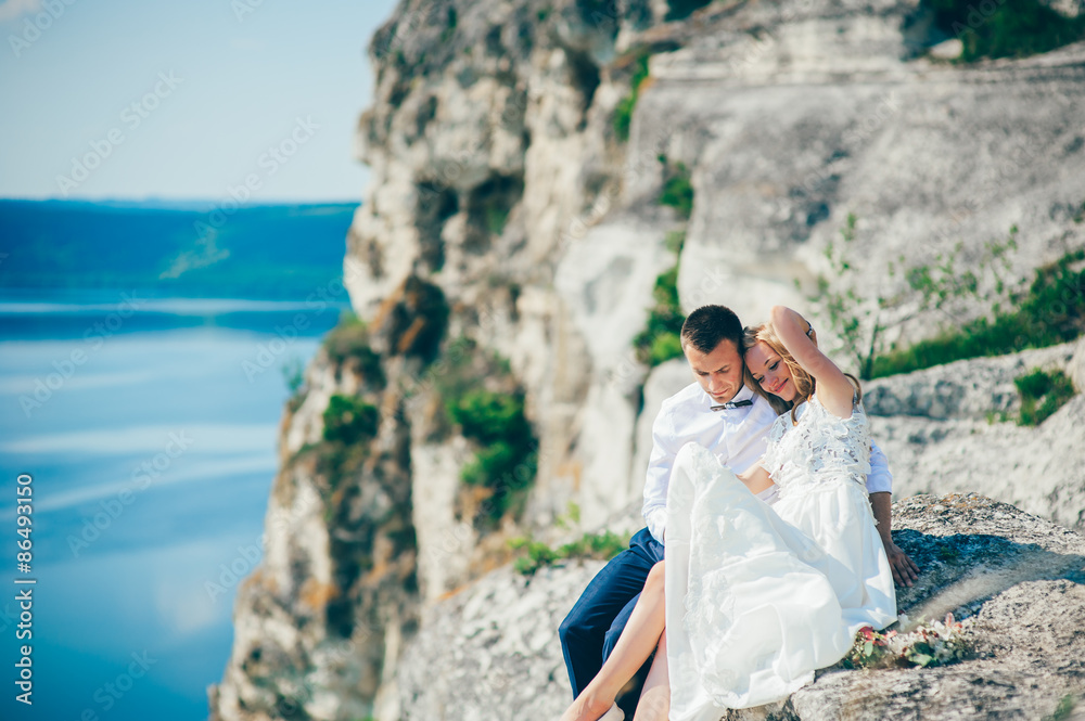 Fototapeta premium beautiful young couple posing on the rock near the lake
