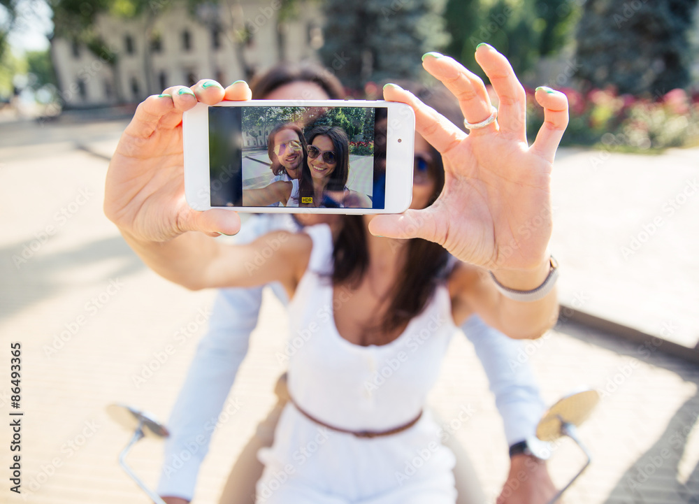 Happy couple showing smartphone screen while making selfie  outdoors