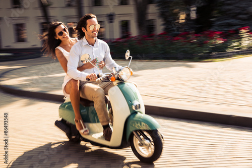 Cheerful young couple riding a scooter