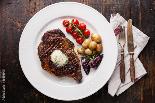 Grilled steak Ribeye with herb butter and baby potatoes on white