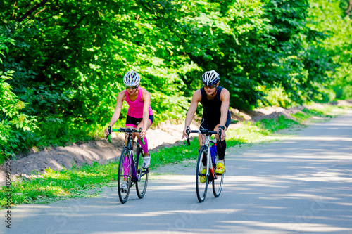 Young pair of professional cyclists riding on the road 