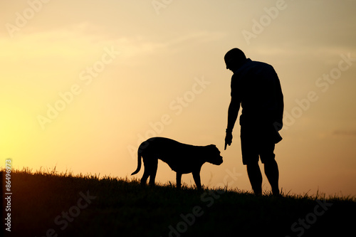 Hund und Herrchen als Silhouette bei Sonnenuntergang