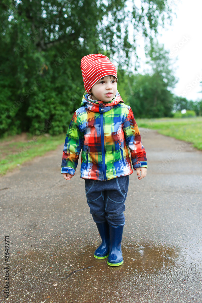 Cute boy in wellingtons walking after rain Cute boy in wellingtons walking after rain