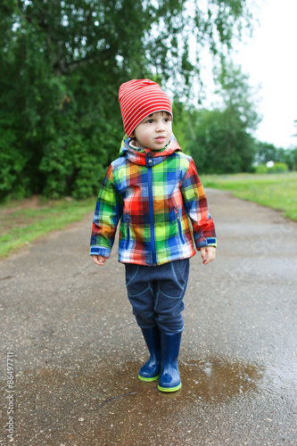 Cute boy in wellingtons walking after rain