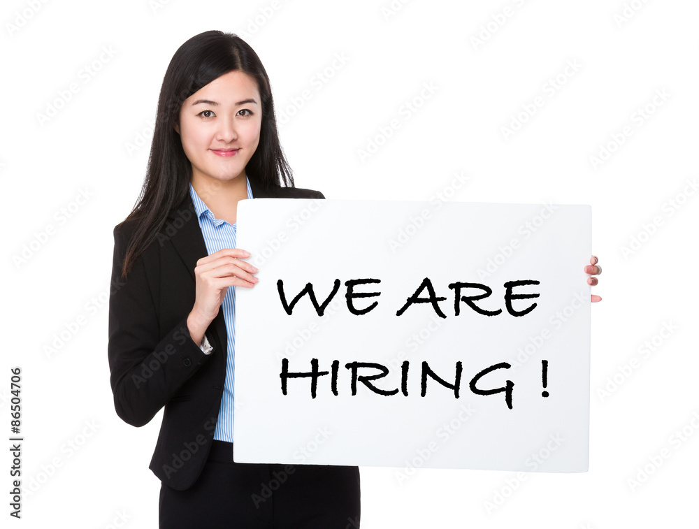 Young businesswoman showing a board showing with we are hiring p Young businesswoman showing a board showing with we are hiring p