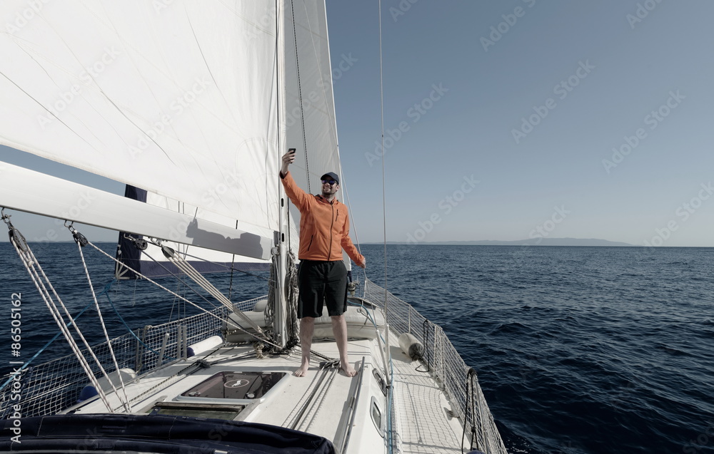 Fototapeta premium Man sailing with sails out on a sunny day and making selfie