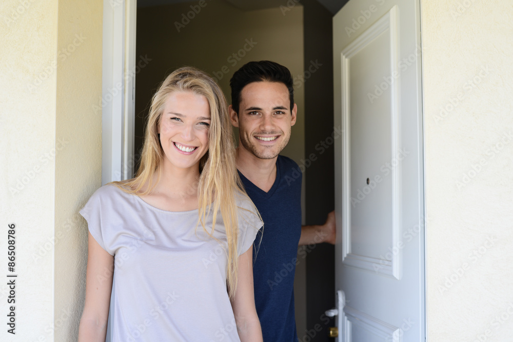 happy young couple man and woman opening door of their new home entrance happy young couple man and woman opening door of their new home entrance