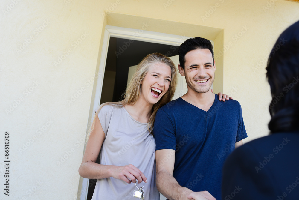 happy young couple with a real estate agent getting keys in front of their new house happy young couple with a real estate agent getting keys in front of their new house