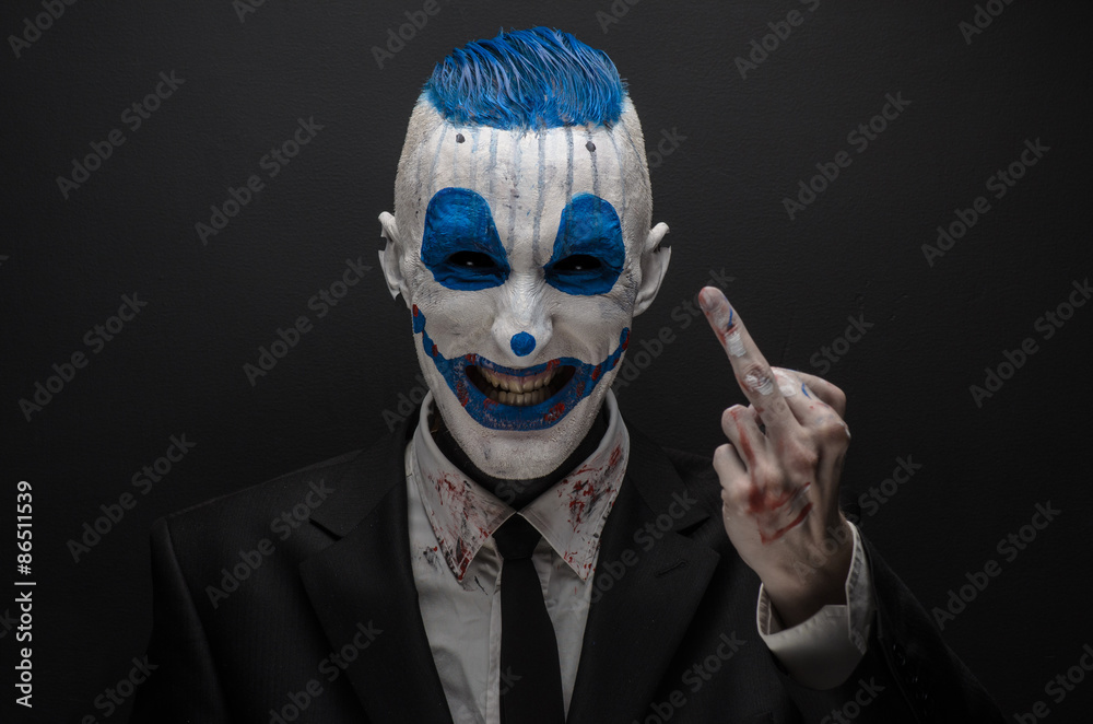 Fototapeta premium Terrible clown and Halloween theme: Crazy blue clown in black suit isolated on a dark background in the studio