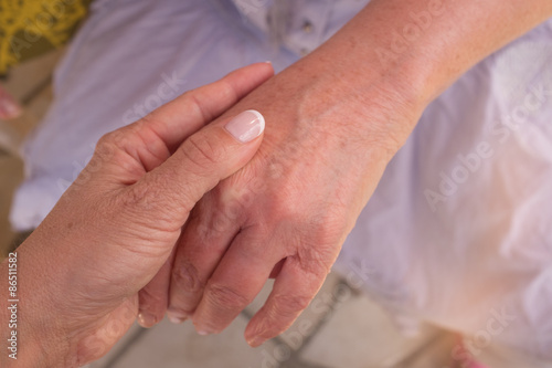 Hands of an elderly woman holding the hand of a younger woman. © OceanProd