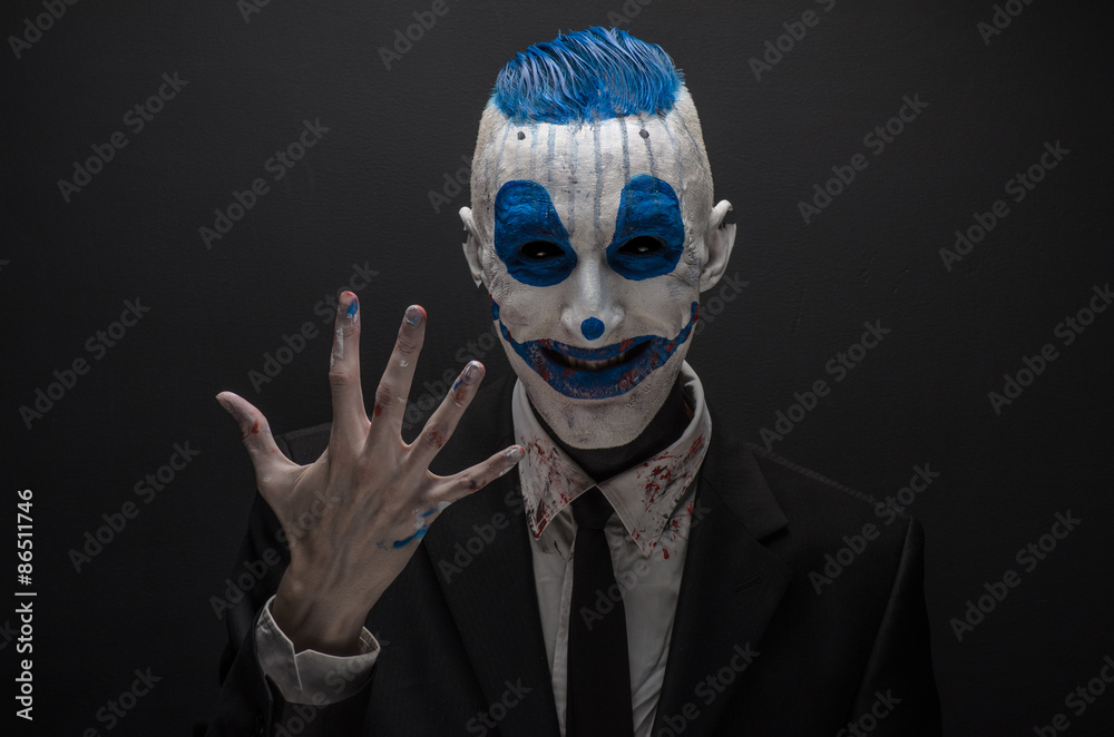 Terrible clown and Halloween theme: Crazy blue clown in black suit isolated on a dark background in the studio Terrible clown and Halloween theme: Crazy blue clown in black suit isolated on a dark background in the studio