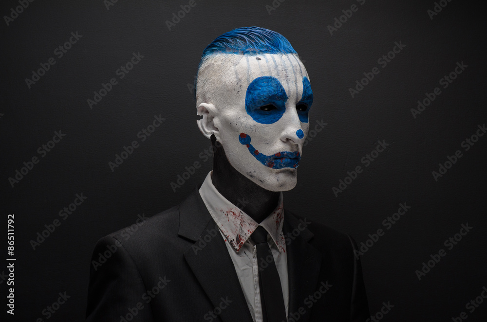 Terrible clown and Halloween theme: Crazy blue clown in black suit isolated on a dark background in the studio Terrible clown and Halloween theme: Crazy blue clown in black suit isolated on a dark background in the studio