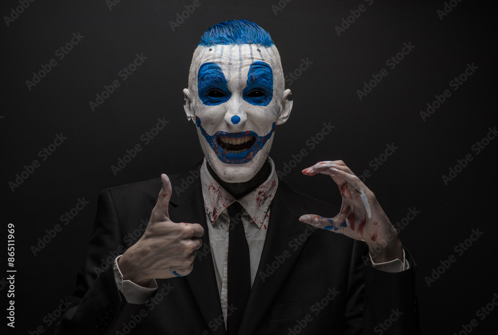 Terrible clown and Halloween theme: Crazy blue clown in black suit isolated on a dark background in the studio Terrible clown and Halloween theme: Crazy blue clown in black suit isolated on a dark background in the studio