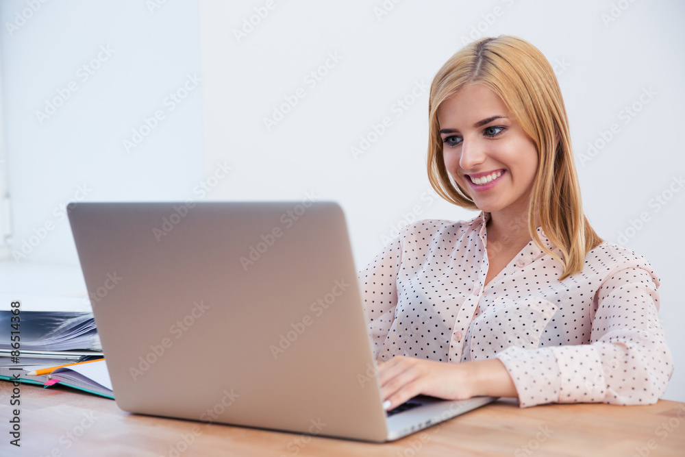 Smiling businesswoman using laptop in office Smiling businesswoman using laptop in office