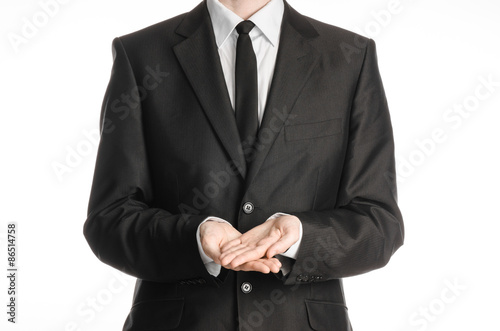 Businessman and gesture topic: a man in a black suit and tie two hands clasped in front of him isolated on a white background in studio