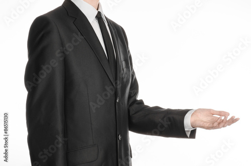 Businessman and gesture topic: a man in a black suit and tie holding his hand in front of him isolated on a white background in studio