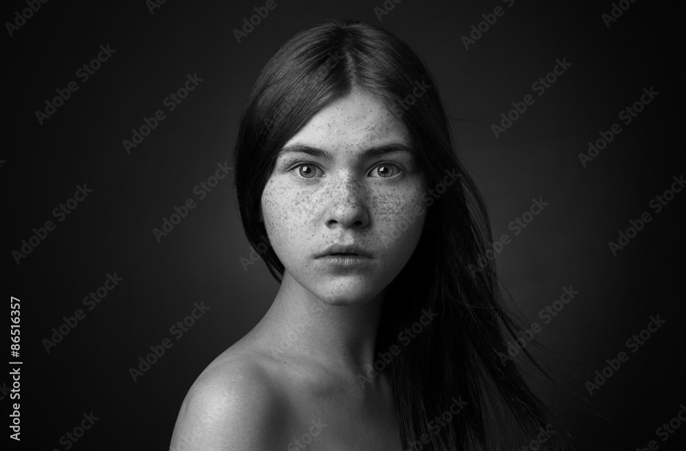 Dramatic portrait of a girl theme: portrait of a beautiful lonely girl with flying hair in the wind isolated on dark background in studio