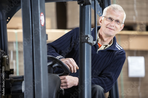 Confident Worker In Forklift At Warehouse