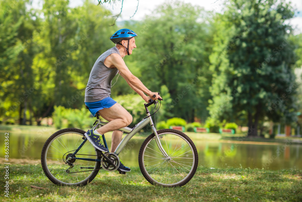 Joyful senior man riding a bike in a park Joyful senior man riding a bike in a park
