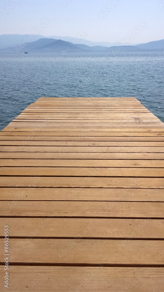 A wooden bridge over the sea and the mountains