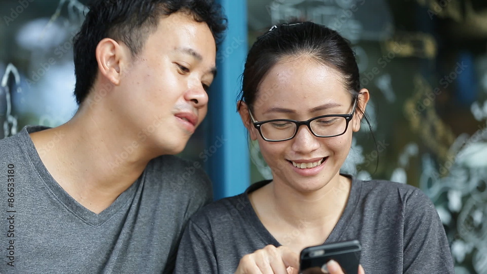 Happy asian man with girl friend using cell phone together ,are selfy Happy asian man with girl friend using cell phone together ,are selfy